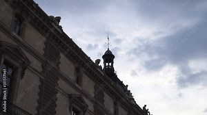 Facade of the Louvre Palace. A weather vane is installed on the roof pointing to four cardinal points. Amazing French Renaissance architecture. Blue sky and white clouds on the background. Ultra HD