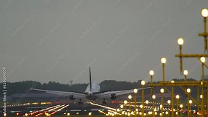 Cinematic footage of a commercial passenger plane landing. Runway brightly lit with landing lights. Tourism and travel concept
