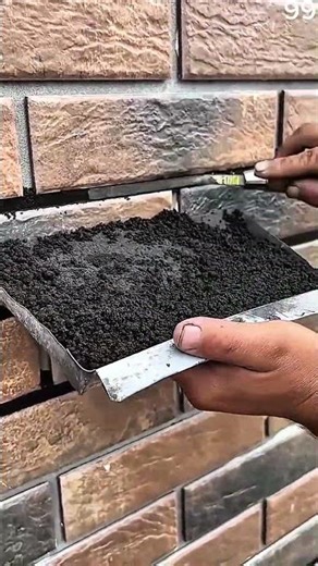 Pressing mortar into brick wall joints with trowel