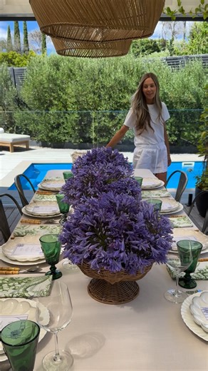 Angie McKenzie | Creative on Instagram: "A summer table in full bloom 💜 Baskets overflowing with Agapanthus, soft neutral linens, green glassware catching the light and the gentle hum of a long lunch unfolding poolside – effortless, relaxed and made for lingering 💫 #summertime #summerentertaining #entertainingathome #tablescapeinspo #tablesettingideas"