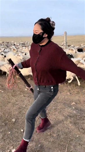This woman is untangling an iron net as she moves her sheep to new pasture