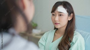 Young beautiful patient woman talking about her pain with female doctor. A woman lies on a hospital bed and doctors are examining her pain.