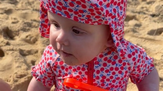 Little toddler girl is enraged because mum won't let her eat beach sand