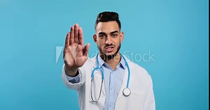 Doctor saying no with stop hand sign over blue background Stock Video