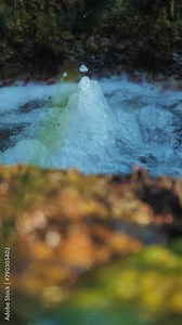 Vertical screen: rushing water pulsates in high bursts in a turbulent natural spring among rocks. Clean drinking water pulsates in a mountain spring. Mineral healing water in the mountains