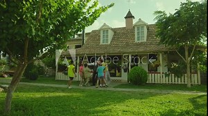 Grandmother and grandfather meeting their grandchildren , kissing , hugging near vintage house . Happy kids visiting village house on summer holidays and running to hug grandparents . Happy moments