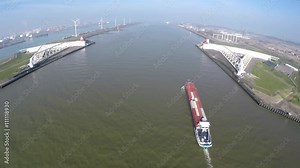Aerial Maeslantkering Maeslant barrier part of Delta Works Delta Werken Deltaworks freight ship moving through large storm surge barrier Rotterdam harbour one of largest moving structures on Earth 4k