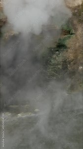 Panning shot, Dragon’s Mouth Spring releasing billows of hot steam and the hot pool of water at Yellowstone National Park in Wyoming.