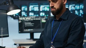 Technician coding in high tech facility with server rows providing computing resources for different workloads. Close up shot of worker overseeing supercomputers operating data