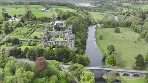 Drone establishing shot of the historic Lismore Castle and gardens with ancient bridge over the Blackwater River tourist location in Waterford Ireland on a tranquil spring day
