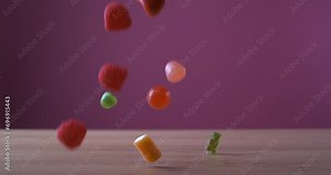 Sweet candies falling in super slow motion captured with a high speed camera on pink background, variety assortment of industrial sugary treats