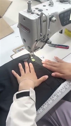 sewing black fabric using an industrial machine for professional garment production activity
