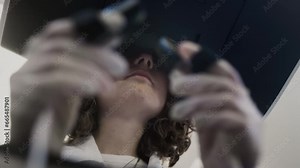 A medic girl controls a medical robot Da Vinci. A woman doctor performs an innovative remote operation. A female holds a surgical scalpel control tool in her hands. Heart treatment in virtual reality