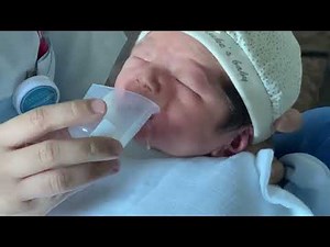 Newborn Baby Theo drinks breast milk from the cup