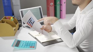 Businessman analyzing chart, thoughtful and calculating.