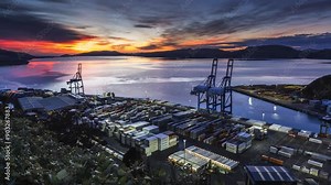 A time-lapse of Port Chalmers in Dunedin as the sun sets with a dramatic sky. Vehicles whiz around loading and stacking shipping containers