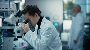Molecular Biology Research Scientist Looking at a DNA Sample Under a Microscope in an Applied Science Laboratory. Portrait of a Young Lab Engineer in White Coat Working on Vaccine Products