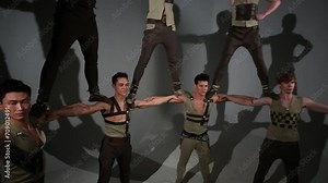 Seven guys in medieval costumes do acrobatic pyramid in studio