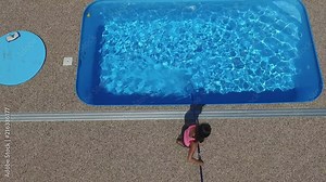 Cleaning the home pool. The woman sucks and cleans the swimming pool. Seasonal work from an aerial perspective.