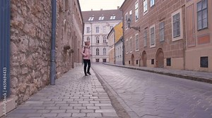Lady admire old architecture street. A young lady with backpack with interest walking in the street between old Europe architecture in the sun light.