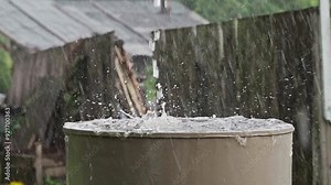 Rain barrel. Strong stream of water pours from the roof into an old metal barrel during heavy rain