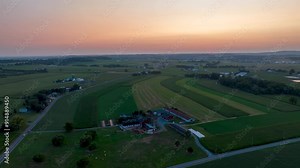 Pennsylvania farmland at sunset with fields and barns. Scenic rural roads stretch through the countryside. Aerial hyper lapse.