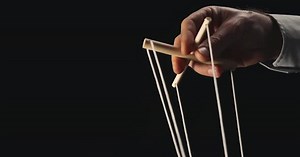The Puppeteer's Hand Controls the Puppet with a Wooden Manipulator and Strings