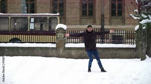 A young guy sliding the slippery street. Funny man feel himself a child and loves wintertime slipping on a road. Slo mo man dangerously slides outdoors during snowing