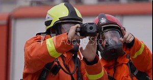 A group of specialized firefighters employs a thermal camera to locate and assess dangerous fire areas, demonstrating their advanced technology and expertise in effectively combating high-temperature