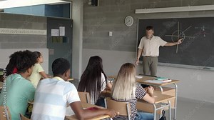 Male math teacher explaining in class to a group of multiethnic teenage students