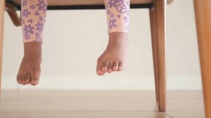 A Childs Small Feet Playfully Hanging from the Edge of a Chair in a Cozy Indoor Space
