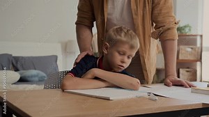 Tilt up shot of teenage boy fell asleep during doing homework while father waking him up at home