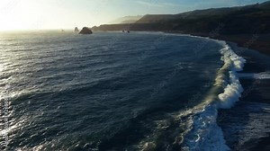 Flying fast backwards down the beach in the Golden hour. Pacific waves sparkling surf break