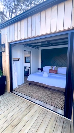 This lakefront container home might be one of the most incredible tiny houses I have ever seen—& best of all, it's a single-level! What do you think? This tiny house was built from a 40' shipping container, with the addition of a small bumpout in the bedroom. Inside, there's a private main-level bedroom, a cozy living space with a couch, a beautiful kitchen with a dining bartop for 2, a full bathroom with an incredible tile shower, & an outdoor living area with a tub overlooking the lake & your 