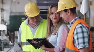 A supervisor stands confidently with workers on the factory line, using a tablet to check the numbers and quality of production.