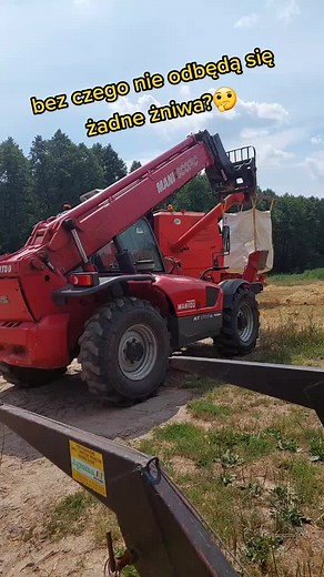 Red Manitou Telehandler Lifting Hay Bale in Open Field