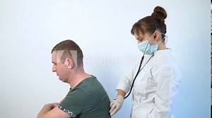 Female doctor using a stethoscope listens to the lungs of a sick male patien at a medical visit in the hospital. Health care concept. Detection covid-19