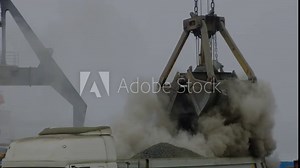 Grapple crane unloading cement clinker from ship to truck in river port. Barge delivery of dusty bulk cargo. Gantry crane unloading and loading in Harbor, outdoors. Logistics. Commerce, nautical