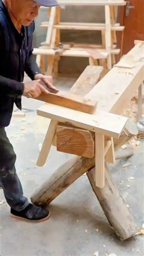 Elderly craftsman hand planing wood on traditional workshop bench