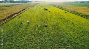 Haystack on field, drone view. Hay bale from residues grass. Hay stack for agriculture. Hay in rolls after combine harvester working in wheat field. Harvest season. Haystacks making.