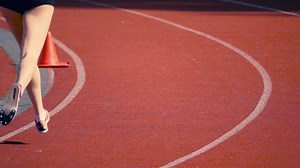Girl in short shorts running sprint on the stadium, slow motion