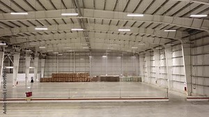 Drone footage inside a spacious warehouse with high ceilings and organized stacks of boxes, ideal for industrial, logistics, and storage-related projects.