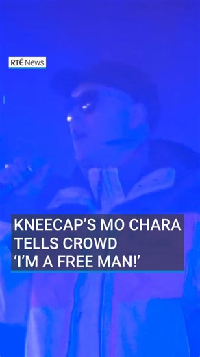 Kneecap band member Liam Óg Ó hAnnaidh, known by his stage name Mo Chara, told the crowd at their sold-out Dublin gig that he was a free man. The Belfast hip hop group performed in Fairview Park a day after Mr Ó hAnnaidh appeared in court in London charged with a terrorism offence. He was granted unconditional bail until his next hearing on 20 August. | RTÉ News