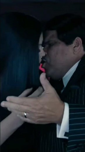 Morticia and Gomez kiss. The family Addams