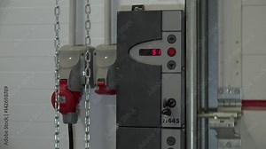 Pressing the control button to open the sectional garage door with a roller mechanism.