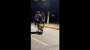 Two Boys Ride a Bicycle Together