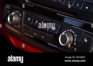 Car climate control system demonstrates the adjustment of temperature and fan settings, emphasizing user interaction with sleek buttons and dials in a contemporary vehicle environment