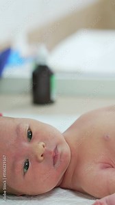 Doctor performs medical procedure to an infant. Newborn baby lying on hospital table. Doctor uses modern medical appliance for treating baby in clinic.. Vertical video