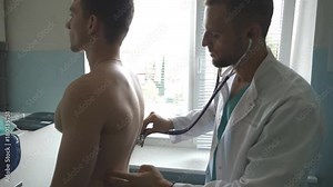 Medic checking back and chest of guy in her office at the hospital. Doctor examining young male patient with stethoscope. Medical worker listening heartbeat of athletic man. Close up