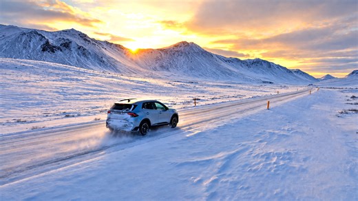 A snow covered road cutting through frozen mountains